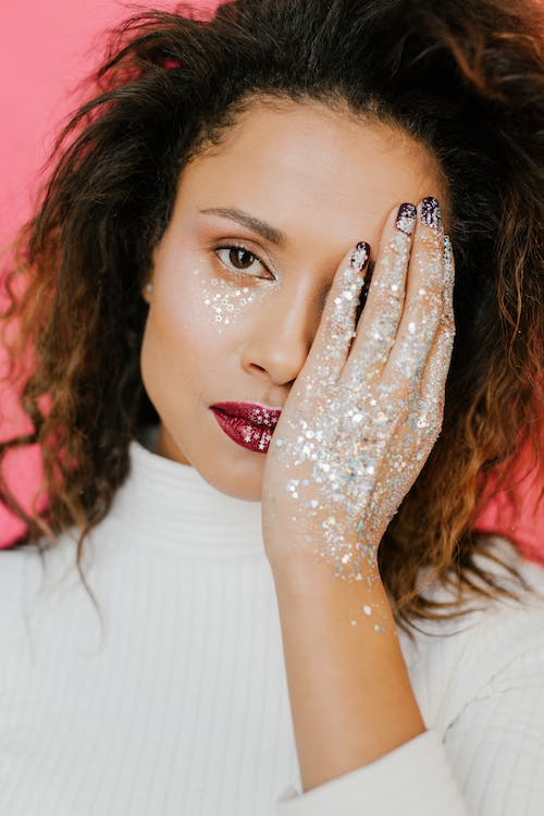 a woman with glitter on her hands, cheeks, and lips