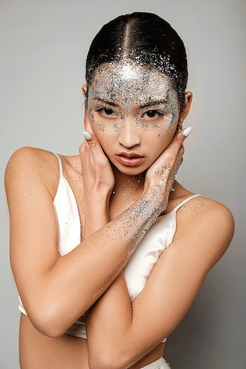 a woman with silver glitter on her forehead, hands, and cheeks