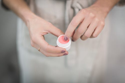 a woman with her finger in a lip balm container