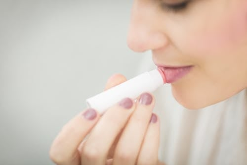 a woman applying a lip balm