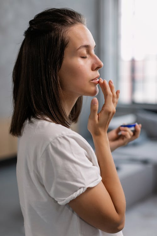 a woman applying lip balm on her lips