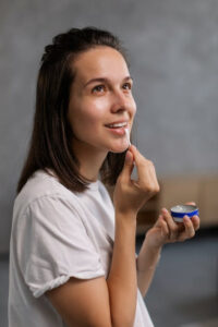 a woman applying lip balm using a Q-tip
