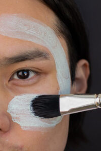 a man applying cream on his face with a brush