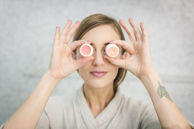a woman holding two lip balm containers in front of her eyes