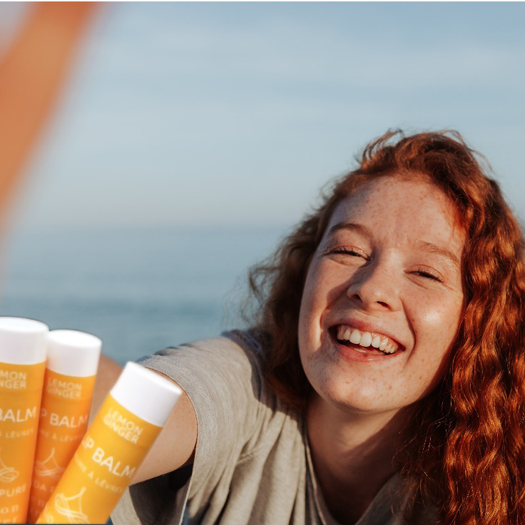 a woman reaching for Lemon Ginger lip balm